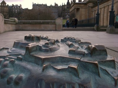 A photo showing part of a bronze relief map with some of Edinburgh's streetscape in the background